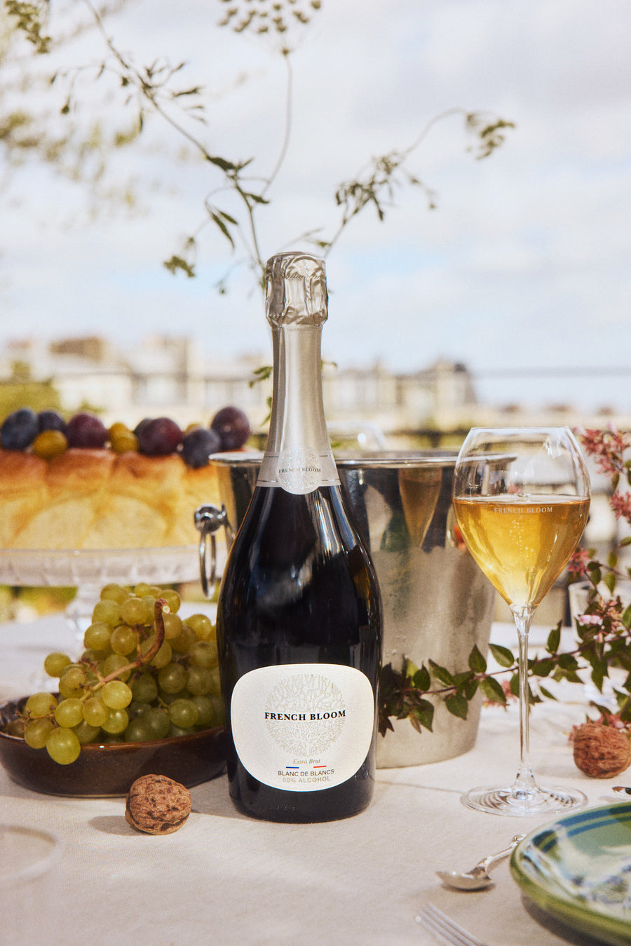 A bottle of French Bloom next to a full flute on a terrace table