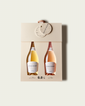 A French Bloom Baby Bloom gift box featuring half bottles of Le Blanc and Le Rosé, with pale golden and pale pink liquid, presented on a light warm-gray background.