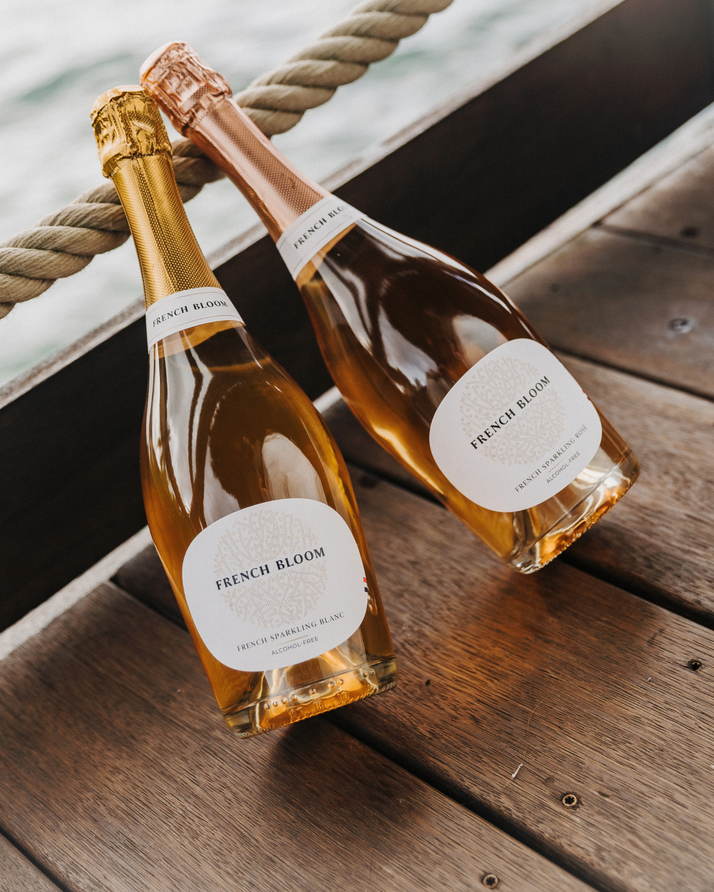 French Bloom Le Blanc and Le Rosé alcohol-free sparkling cuvées on a wooden boat deck.