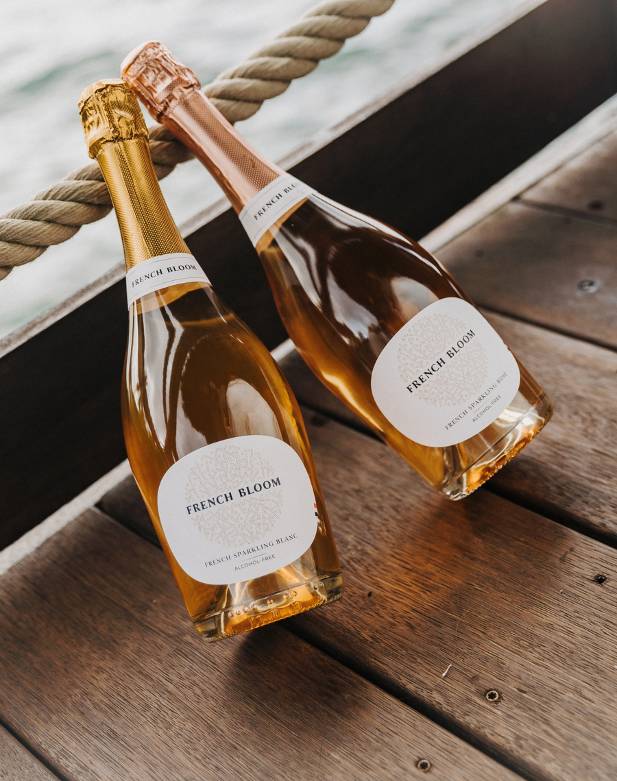French Bloom Le Blanc and Le Rosé alcohol-free sparkling cuvées on a wooden boat deck.