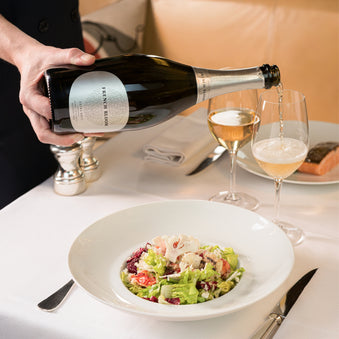 a person pouring a bottle of French Bloom into a wine glass at a restaurant