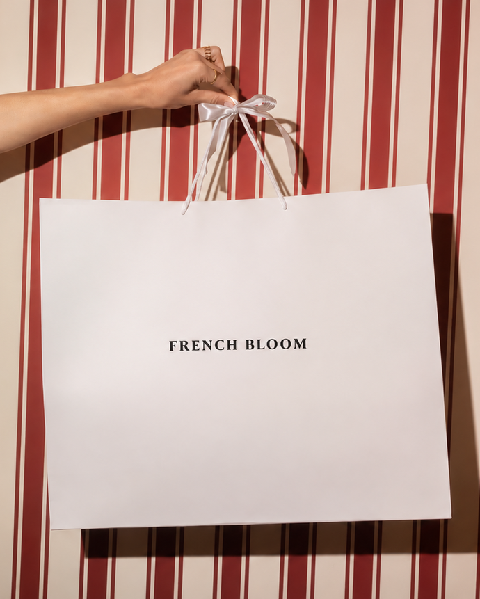 French Bloom gift bag held against an elegant red and cream striped background.