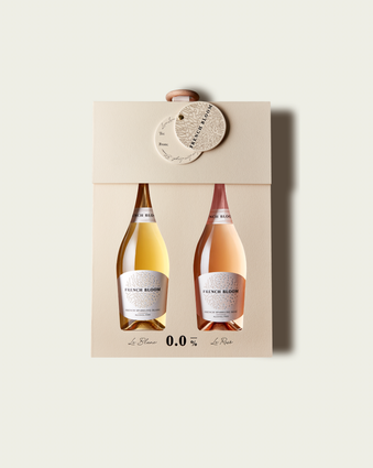 A French Bloom Baby Bloom gift box featuring half bottles of Le Blanc and Le Rosé, with pale golden and pale pink liquid, presented on a light warm-gray background.