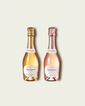 Two French Bloom half bottles, Le Blanc with pale golden liquid and a metallic gold foil top and Le Rosé with pale pink liquid and a metallic rose-gold foil top, set against a light warm-gray background.