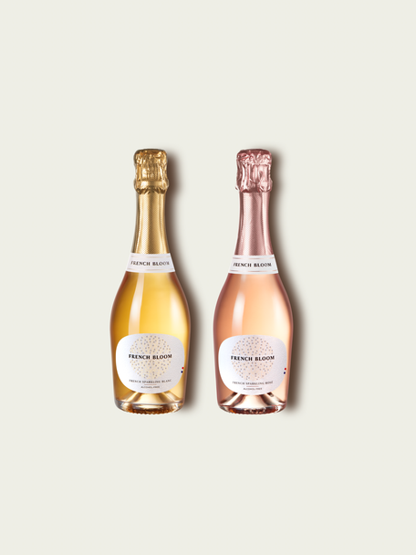 Two French Bloom half bottles, Le Blanc with pale golden liquid and a metallic gold foil top and Le Rosé with pale pink liquid and a metallic rose-gold foil top, set against a light warm-gray background.