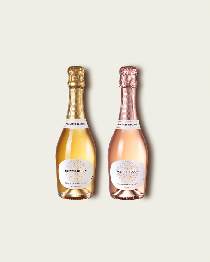 Two French Bloom half bottles, Le Blanc with pale golden liquid and a metallic gold foil top and Le Rosé with pale pink liquid and a metallic rose-gold foil top, set against a light warm-gray background.