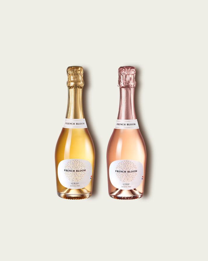 Two French Bloom half bottles, Le Blanc with pale golden liquid and a metallic gold foil top and Le Rosé with pale pink liquid and a metallic rose-gold foil top, set against a light warm-gray background.